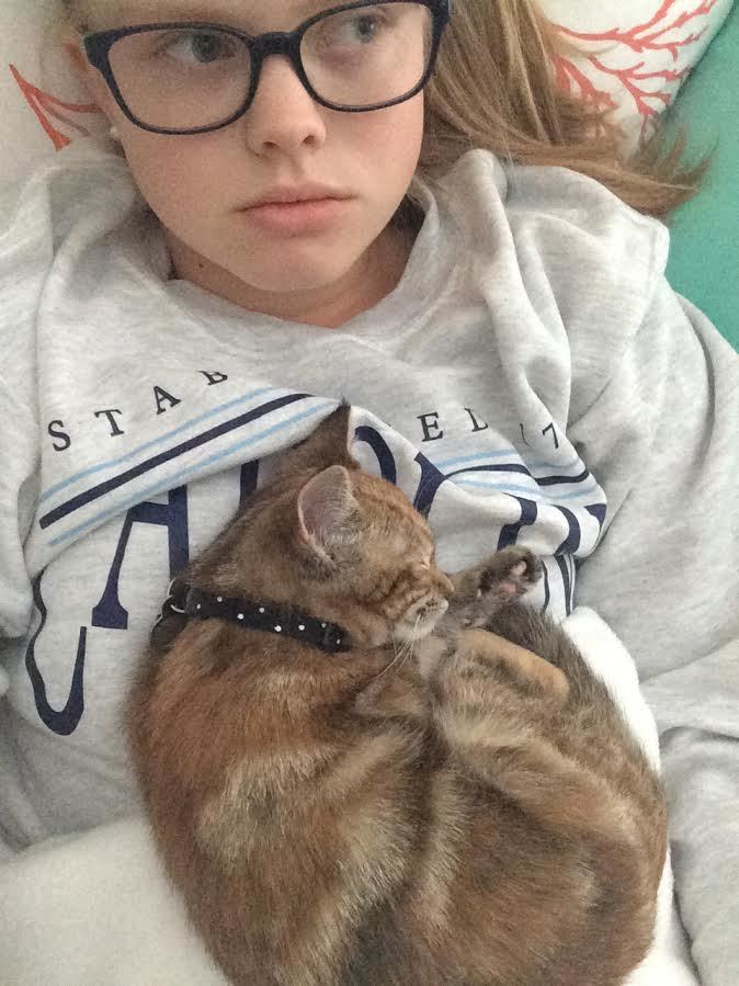 Small kitten sleeps on the chest of a girl in glasses.